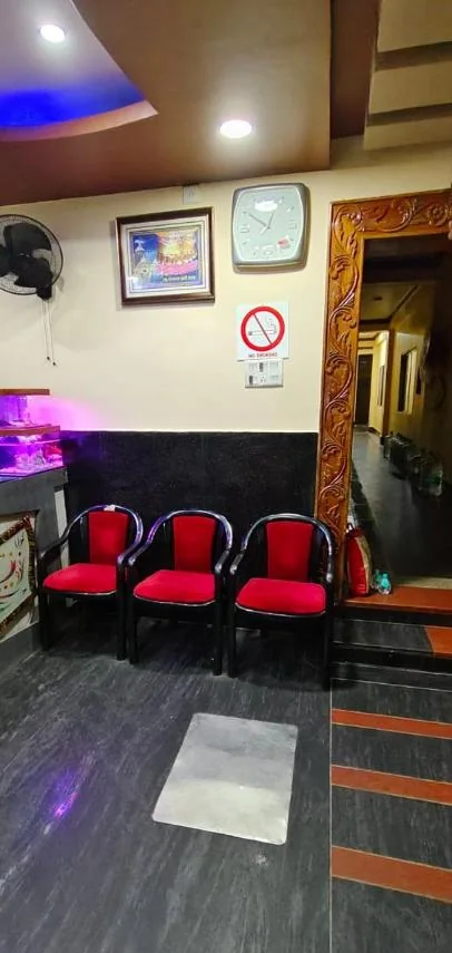 Reception lounge at Hotel JM International with three red chairs and a carved wooden doorway