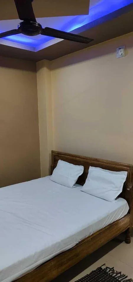 Standard room double bed under a blue LED ceiling and fan