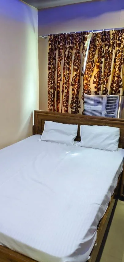 Double bed with white striped linen under brown patterned curtains