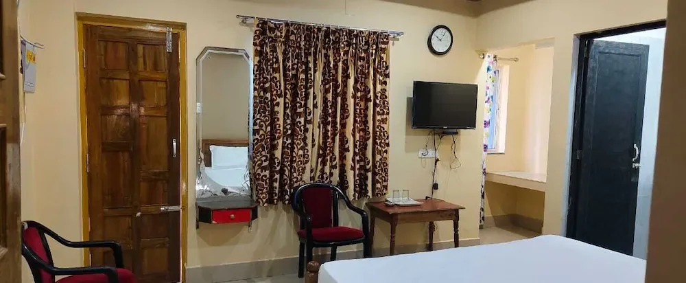 Deluxe AC room with a carved wooden door, dressing mirror, TV and red chairs
