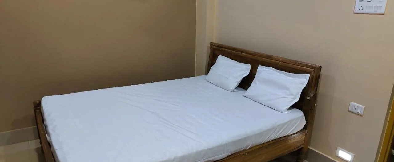 Standard room double bed with two pillows and wall switches