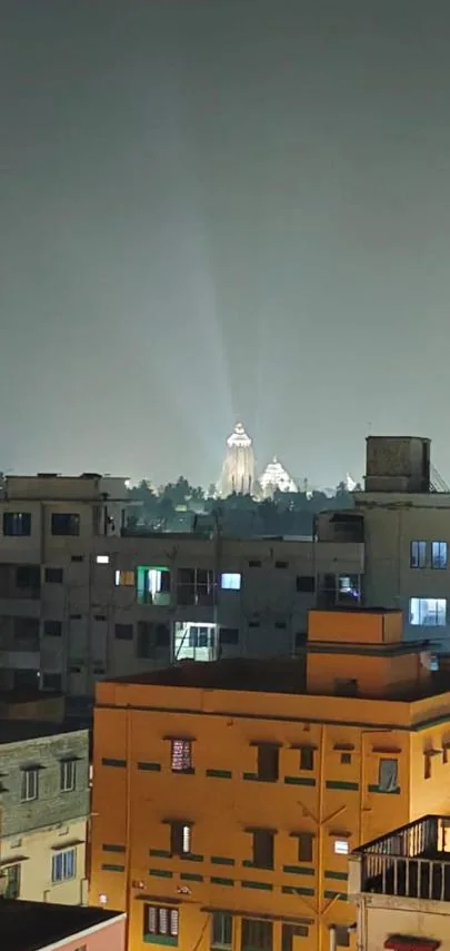 Illuminated Jagannath Temple spire over Puri rooftops at night